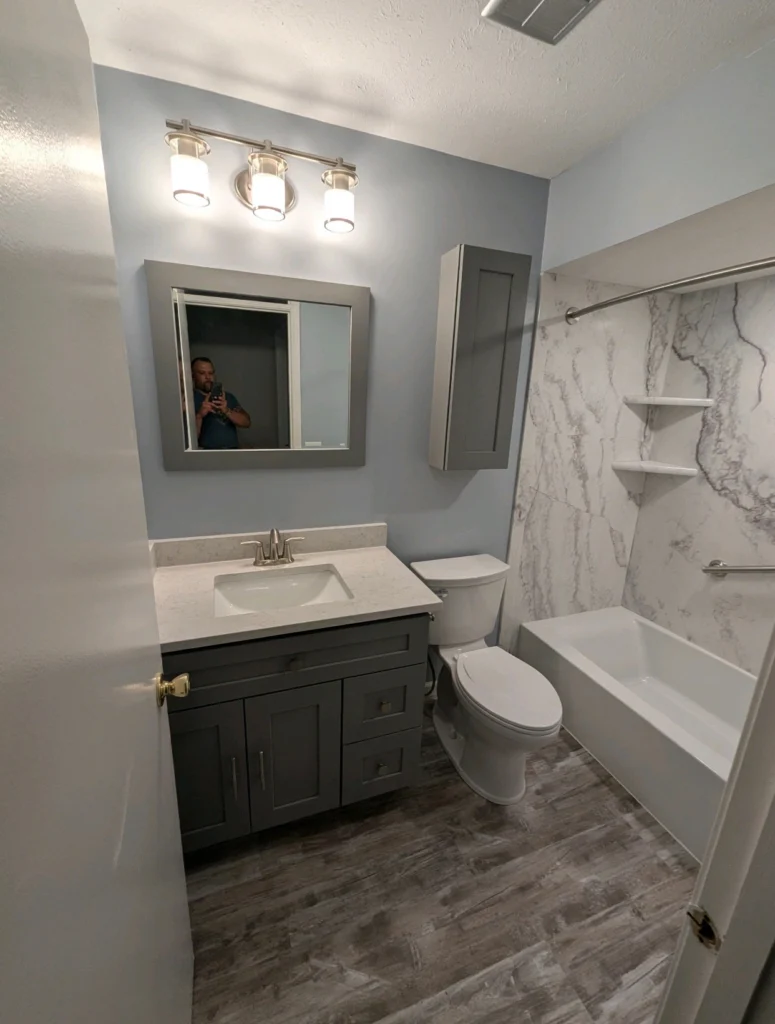 Modern bathroom with gray vanity and tub.