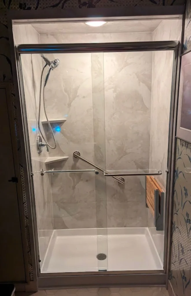 Glass shower with modern fixtures and lighting.