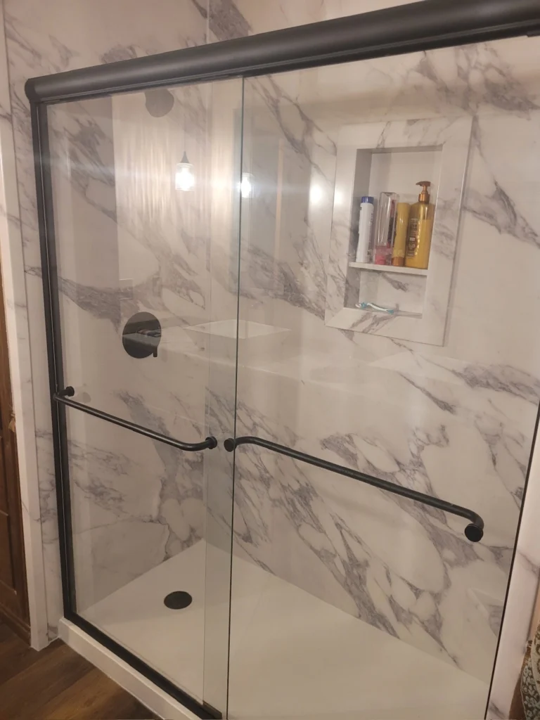 Marble shower with glass doors and shelves.