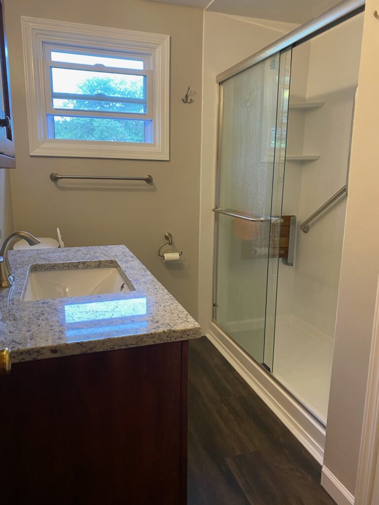 Modern bathroom with granite countertop and glass shower.