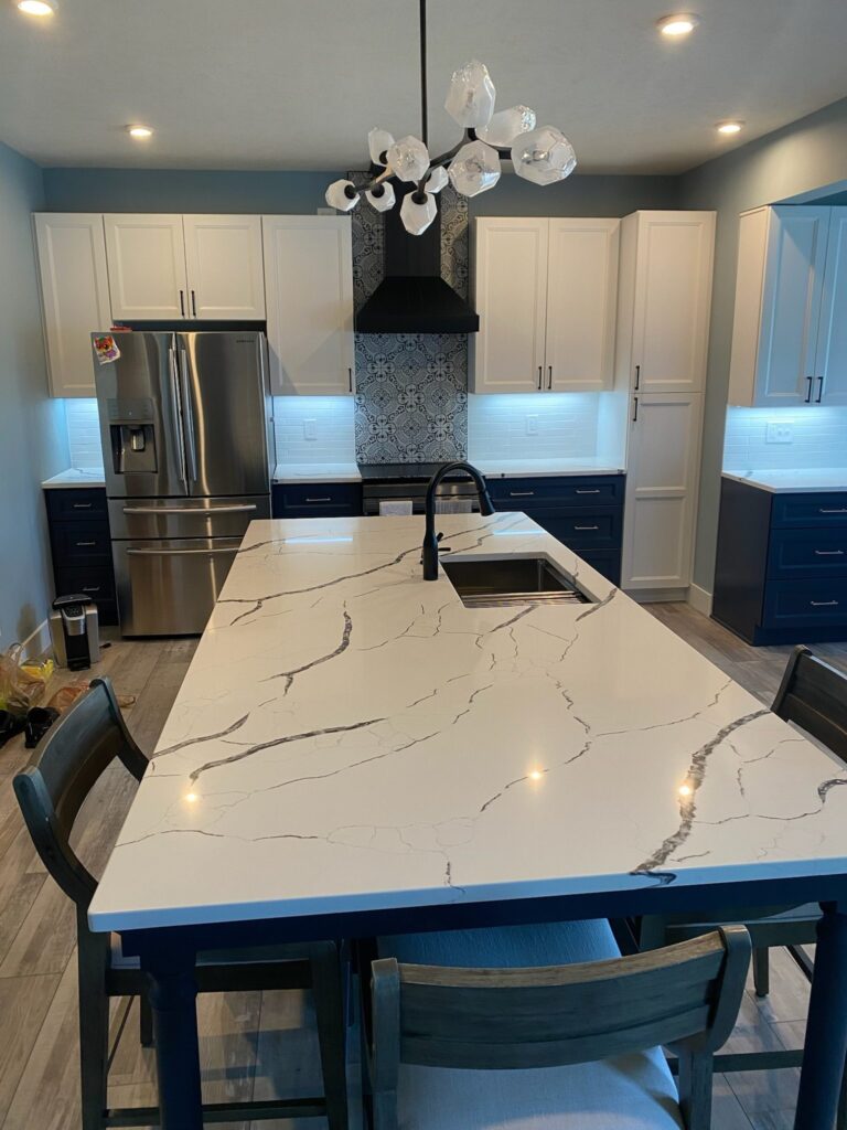 Modern kitchen with a large marble island and stainless steel appliances.