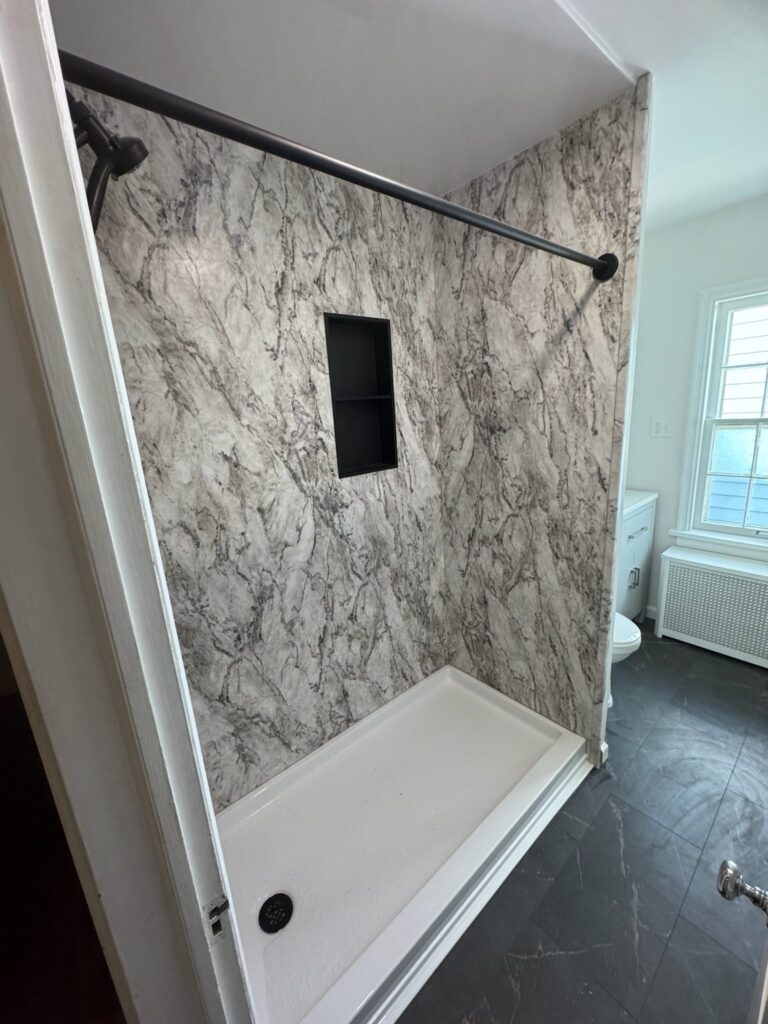 Modern shower with marble-patterned walls and a built-in niche.