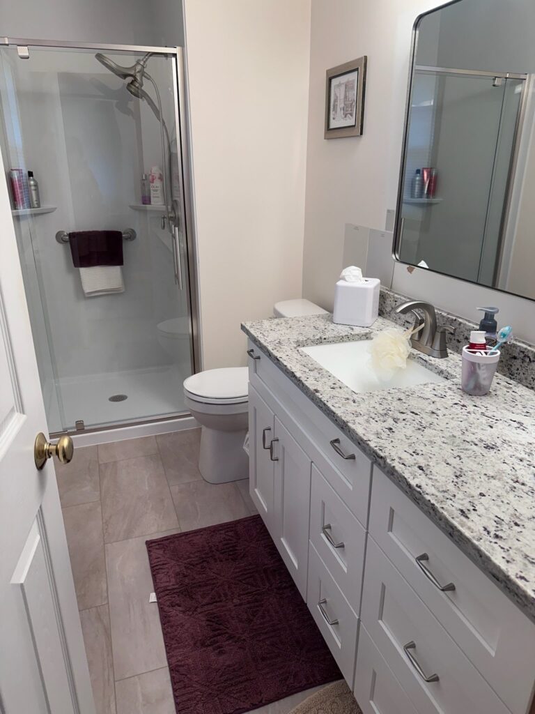 Modern bathroom with granite countertop and glass shower.